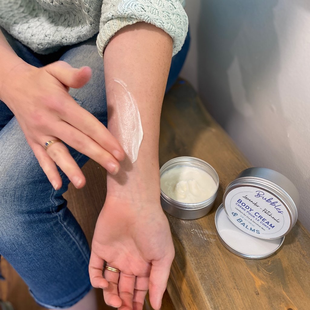 Bubbles &amp; Balms body cream being applied to womans arm showing how it melts over skin for fast absorption.