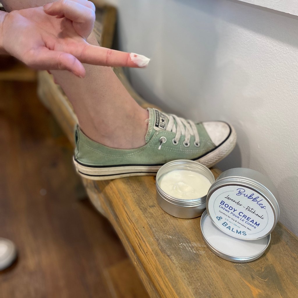 Woman showing how a small amount of Bubbles &amp; Balms body cream can moisturize a significant amount of dry skin.